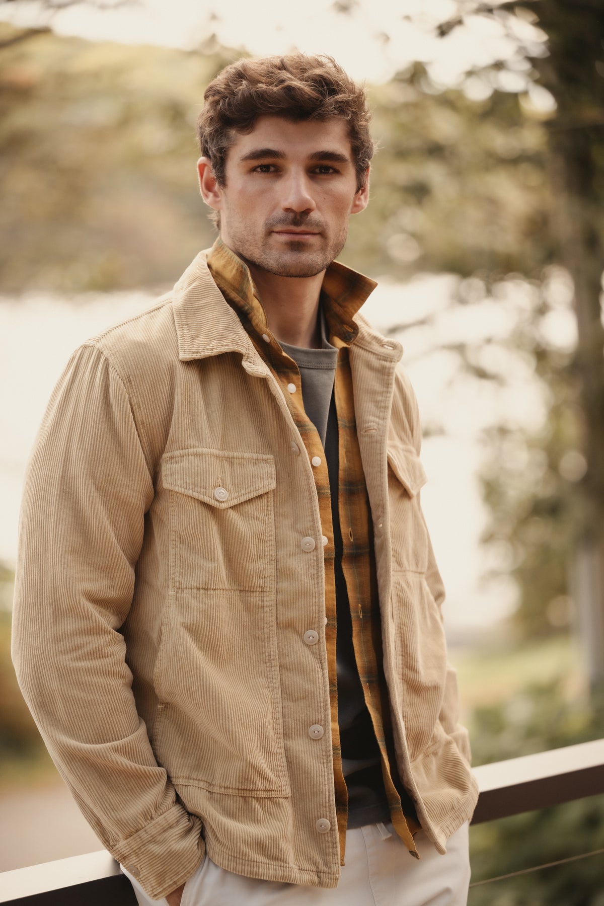 Honey corduroy trucker jacket worn open with flap chest pockets and button front.