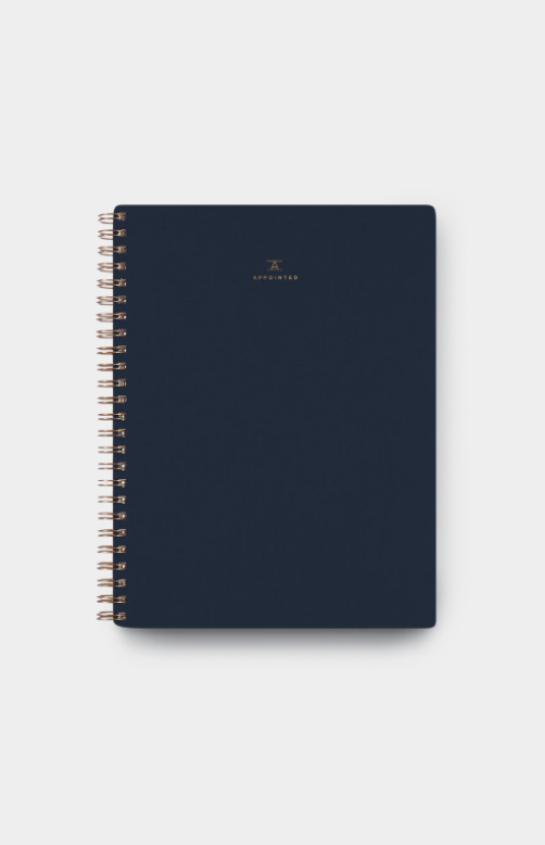 Oxford blue spiral notebook with gold-tone rings and small minimalist cover mark